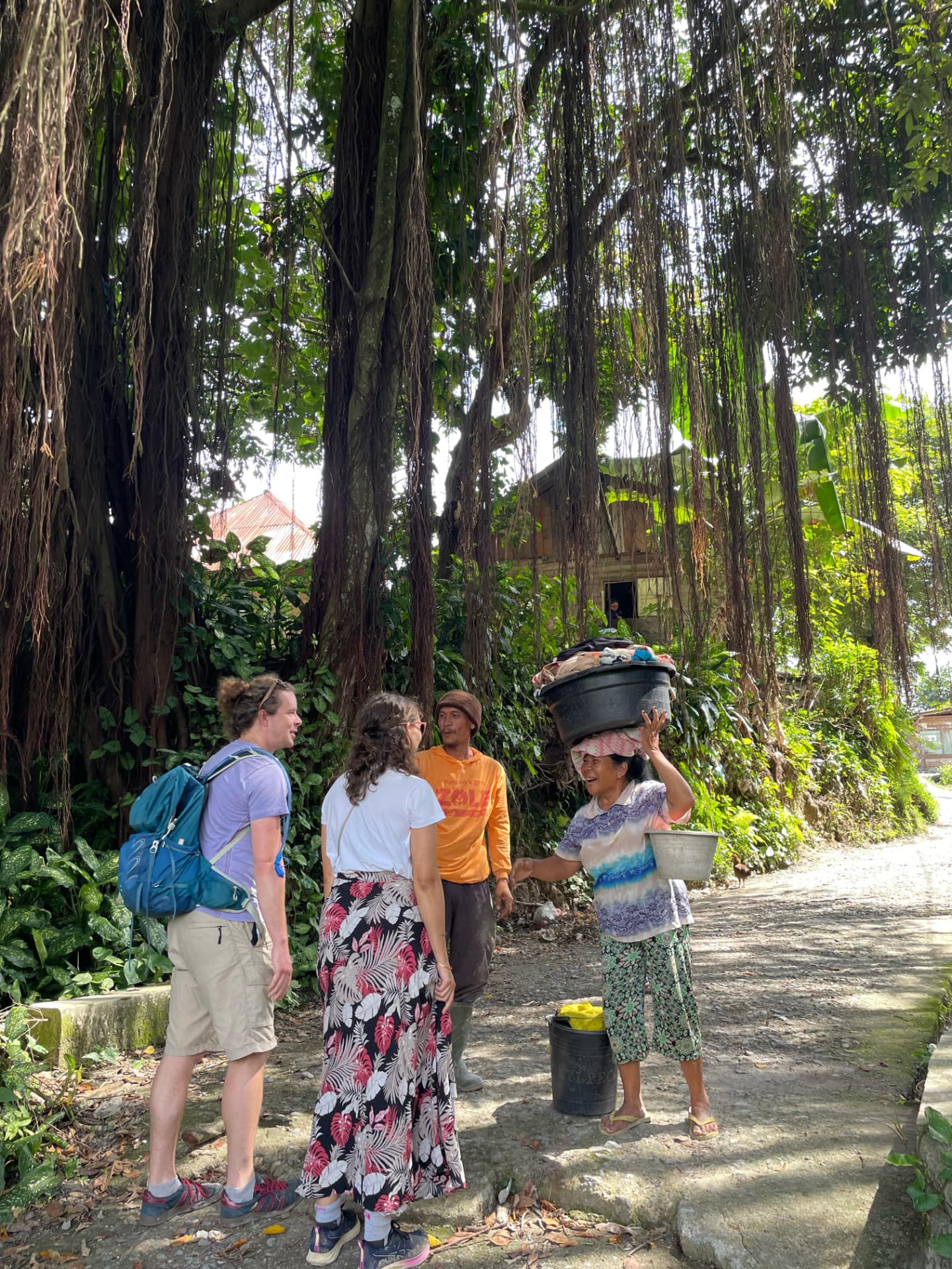 Guests chatting with villagers under a huge banyan tree