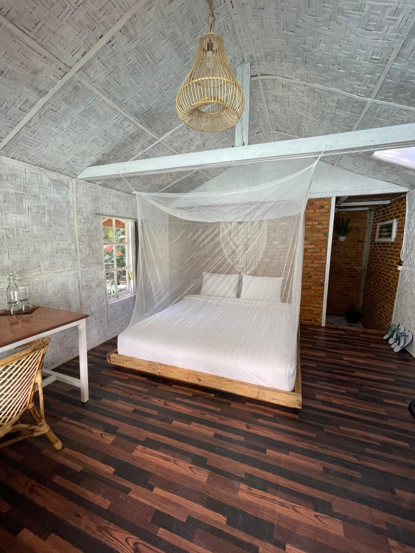 Bamboo house interior with mosquito-netted double bed and woven bamboo walls