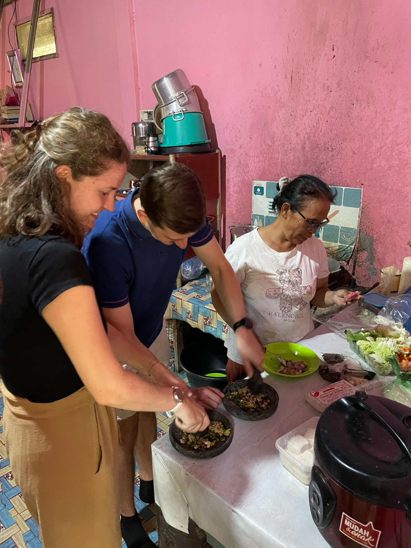 Guests grinding sambal in stone mortars with the Ibu of the house