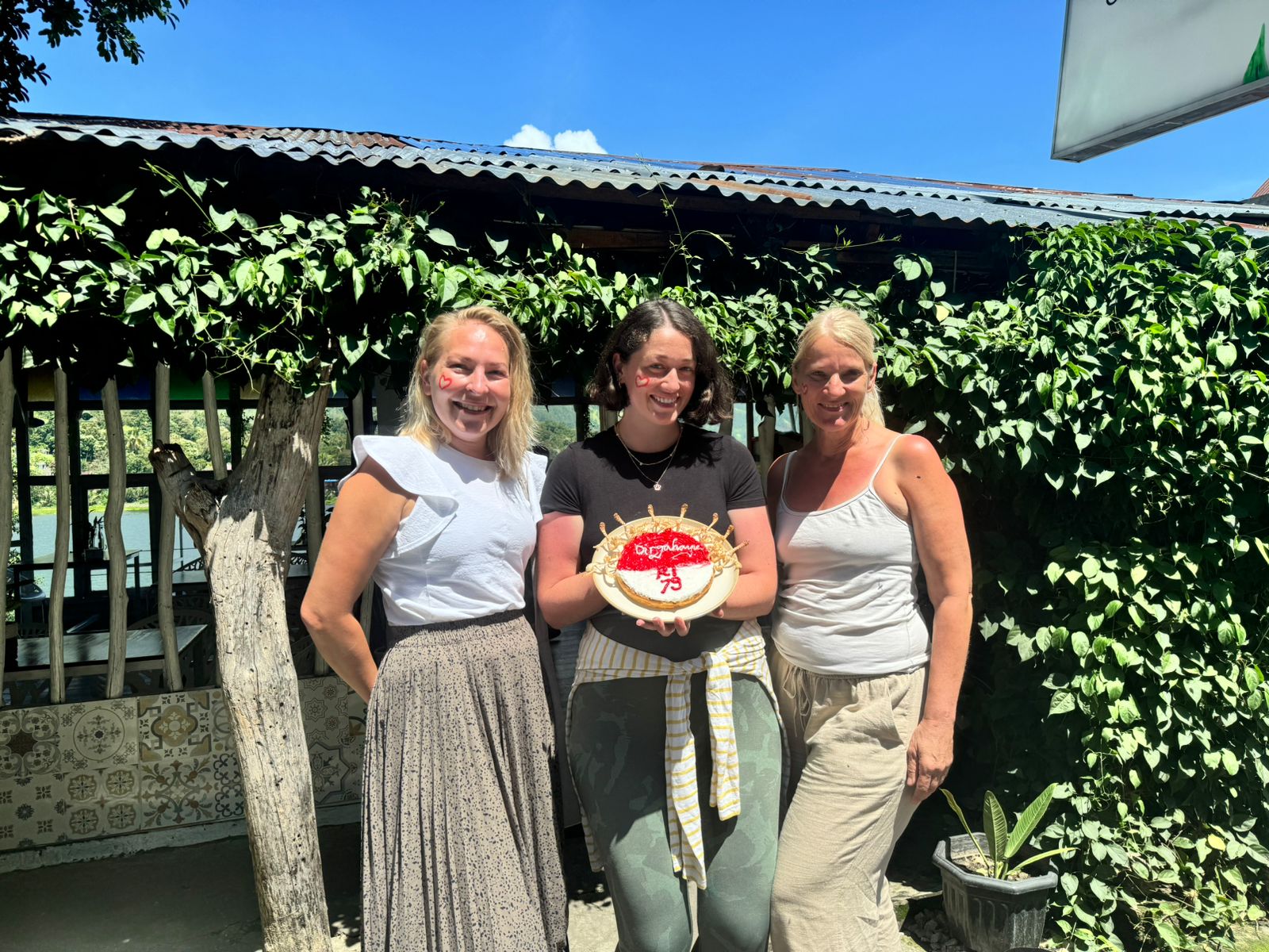 Team and guests with a homemade cake outside the café