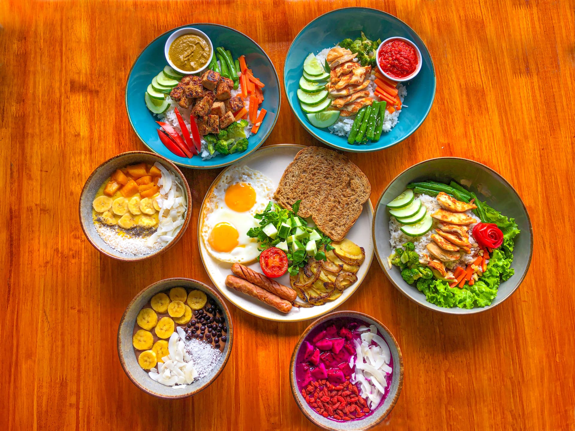 A spread of Hub Tata dishes: rice bowls, breakfast plate and fruit bowls