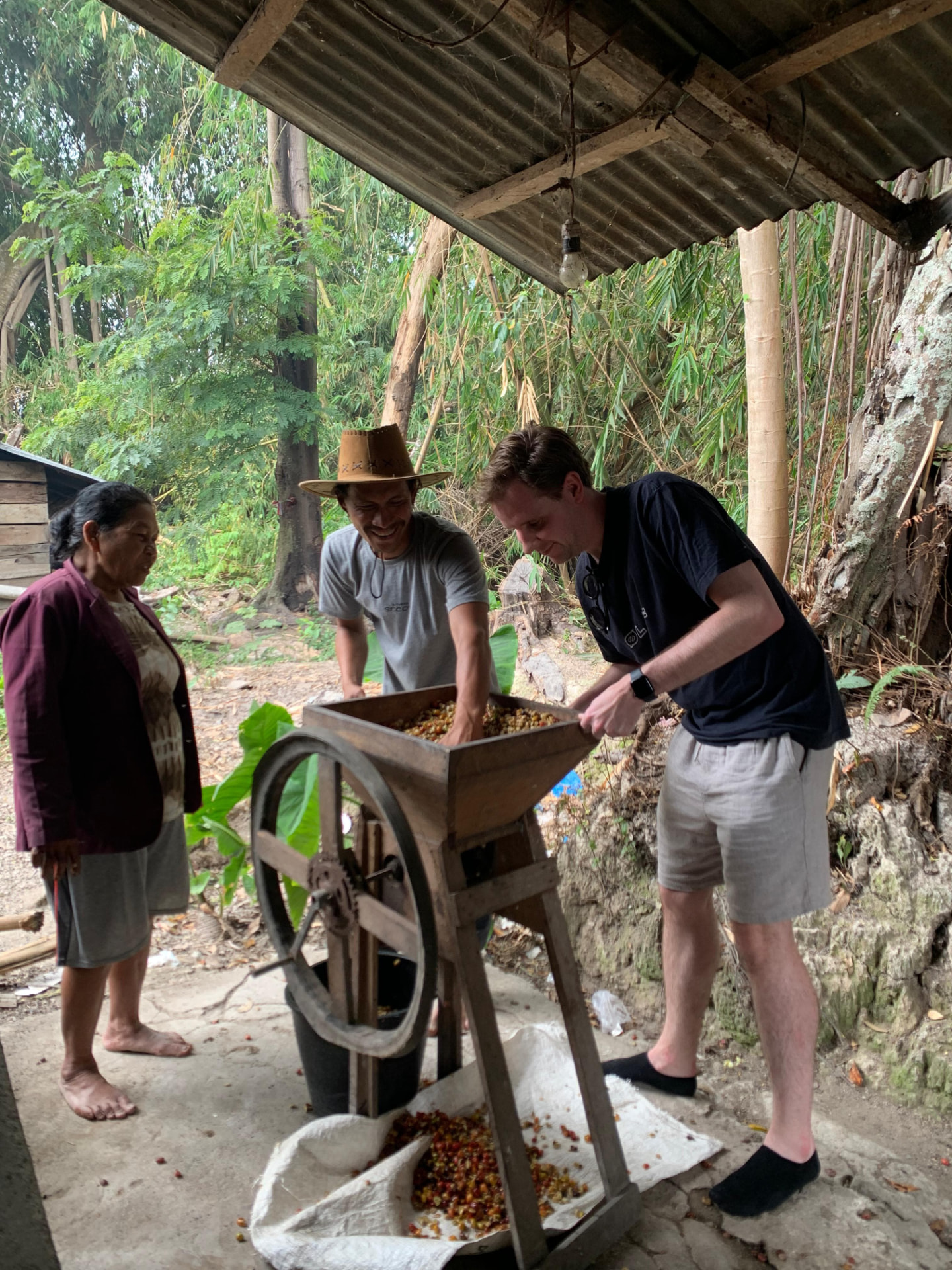 A guest grinding freshly picked coffee cherries with the farmer