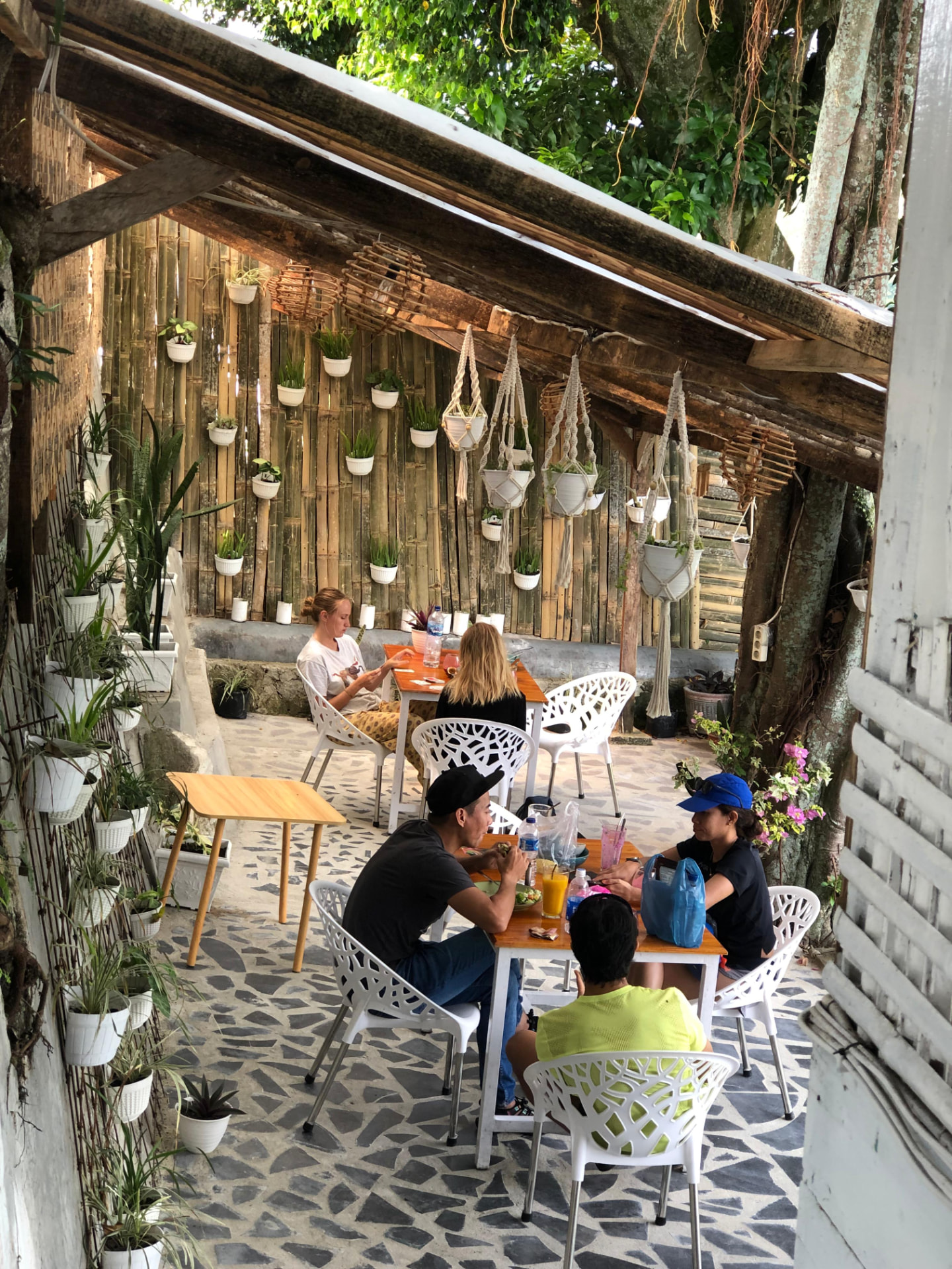 Guests eating together on the leafy café terrace at Hub Tata