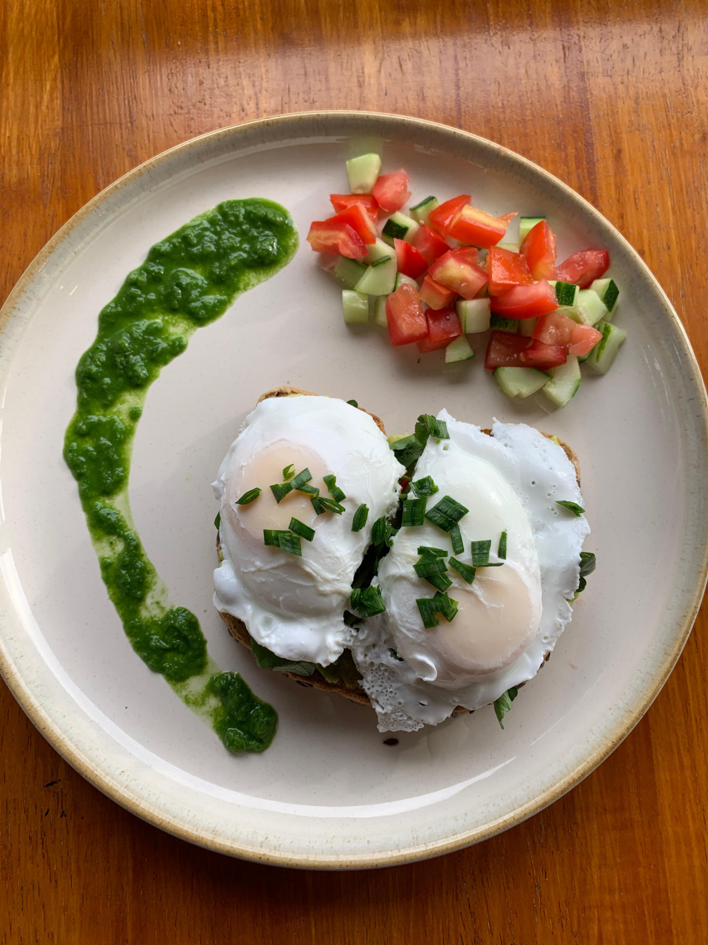 Poached eggs on toast with herb sauce and fresh tomato-cucumber salad