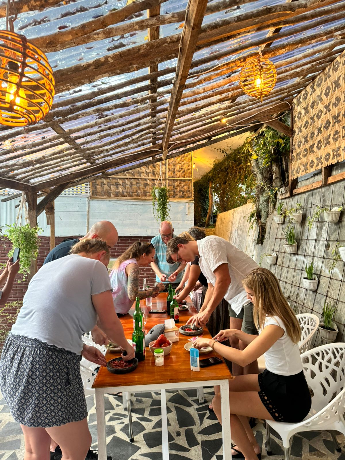 A group working together on sambal at the long table under the terrace