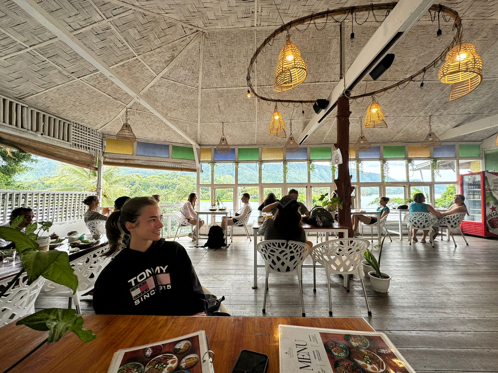 Busy café hall with lake and hill views through the windows