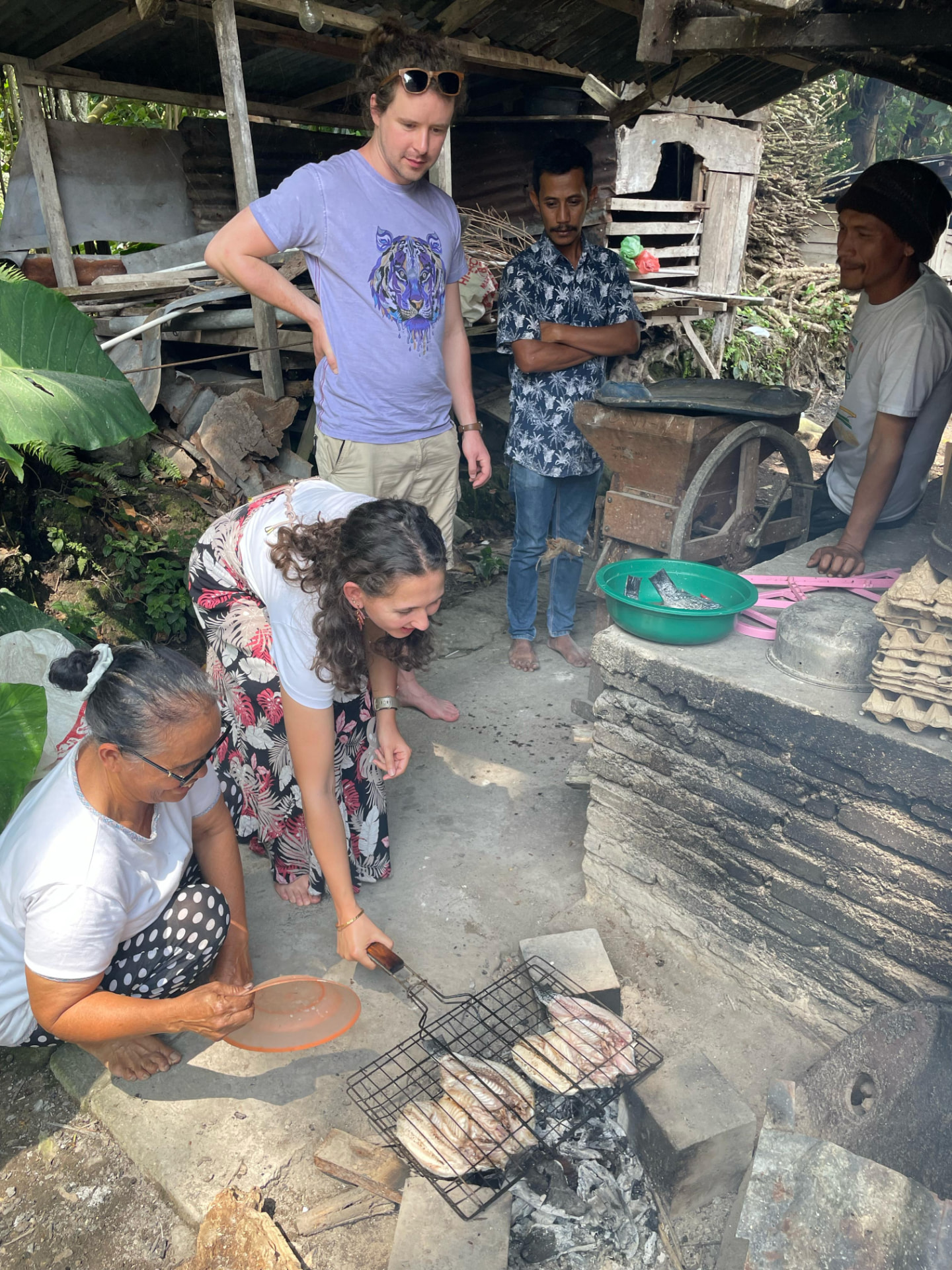 Guests helping with the fish barbecue over an open fire