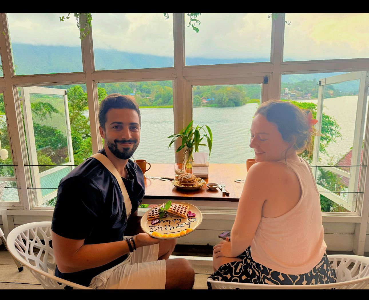 A couple with a birthday waffle at a lakeside window table