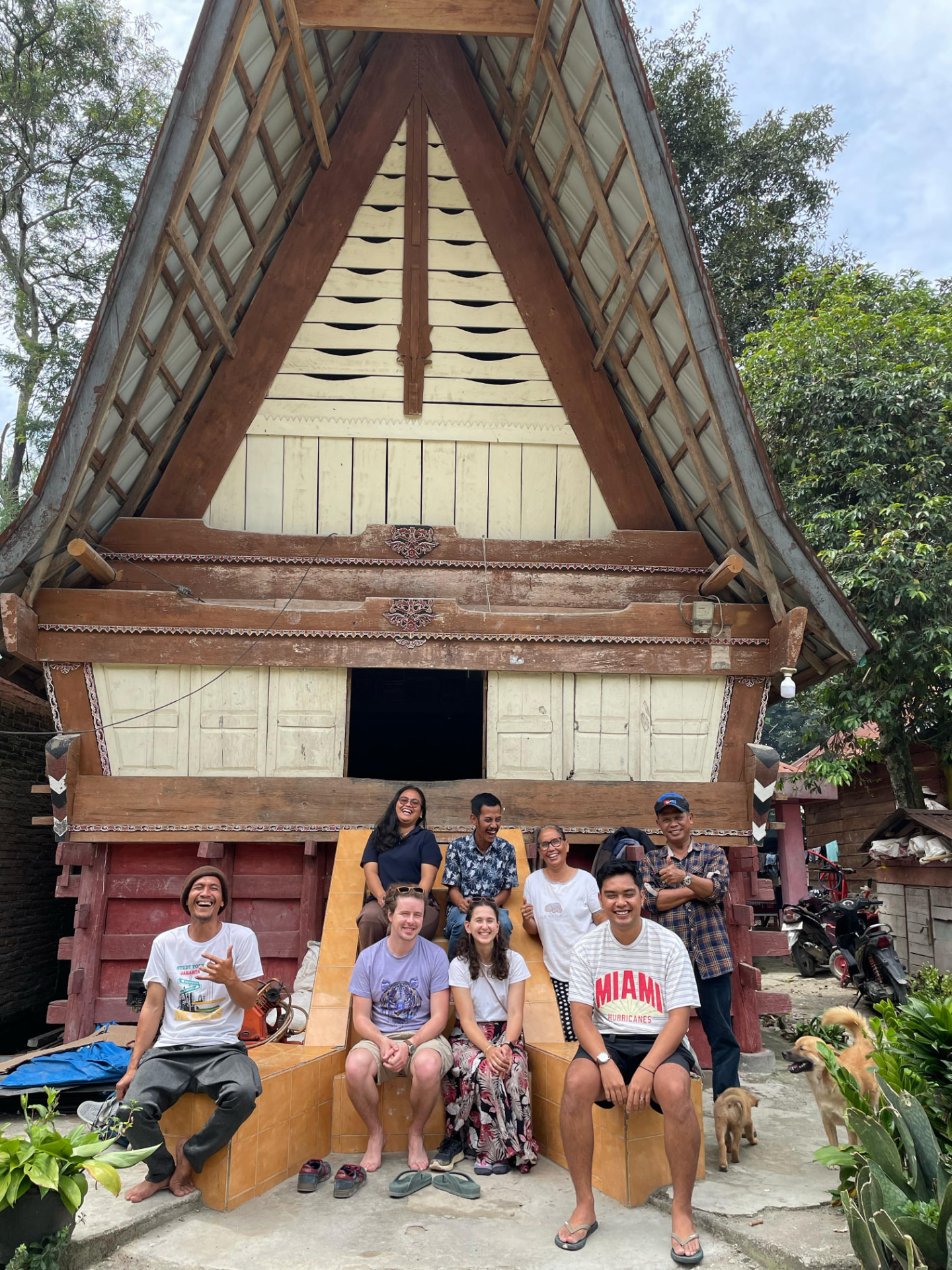 Guests and the farmer's family in front of a traditional Batak Rumah Bolon