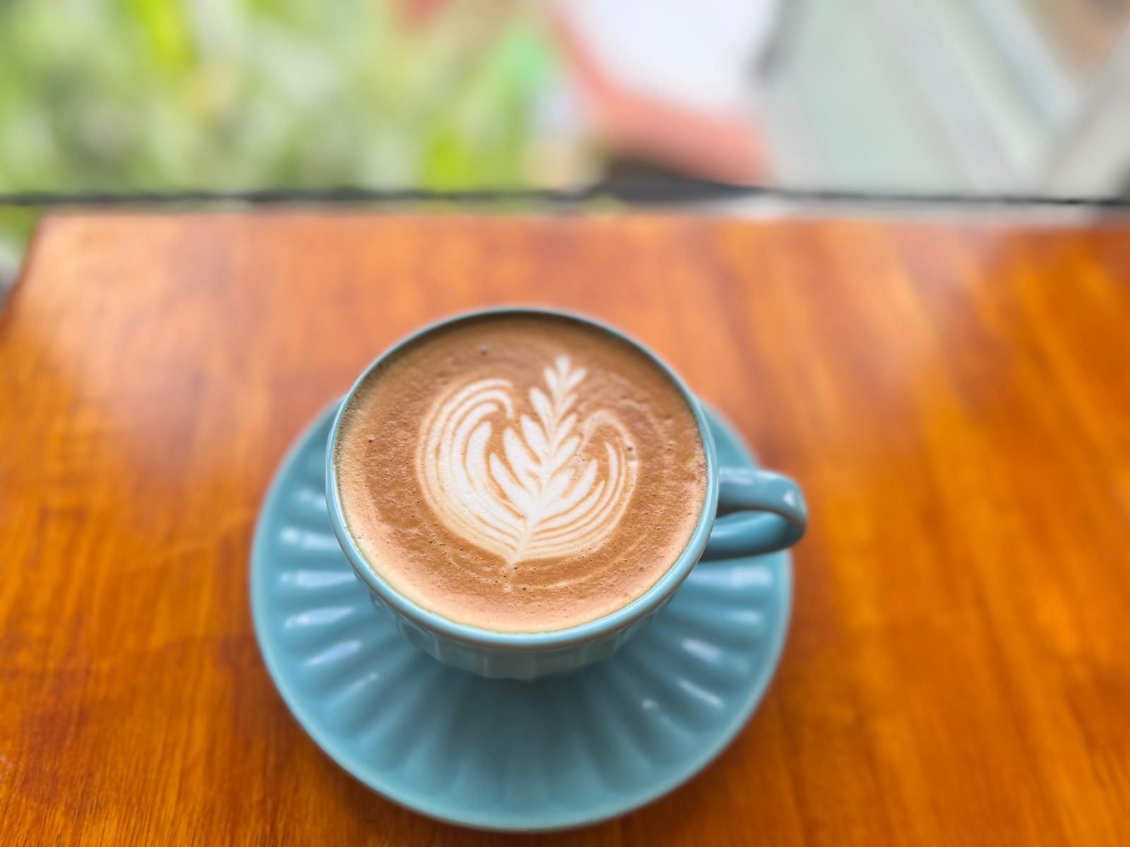 Latte with heart art in a blue cup on a wooden table